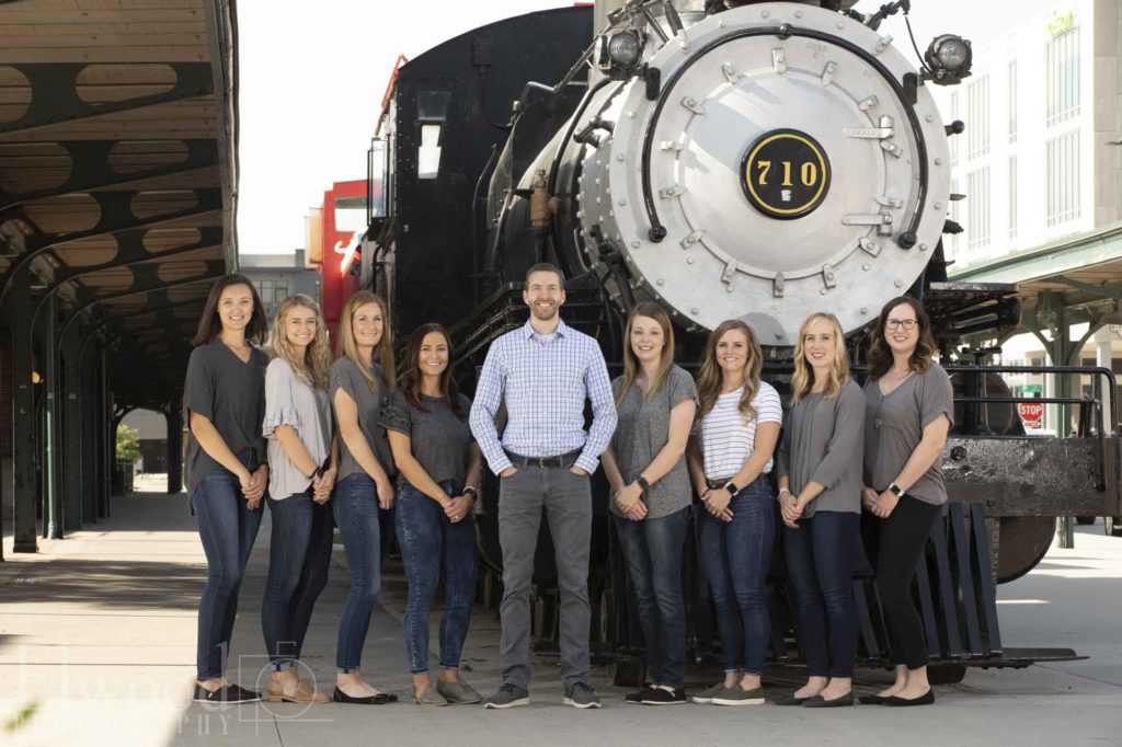 team members of wilderness station pediatric dentistry standing in front of a black train