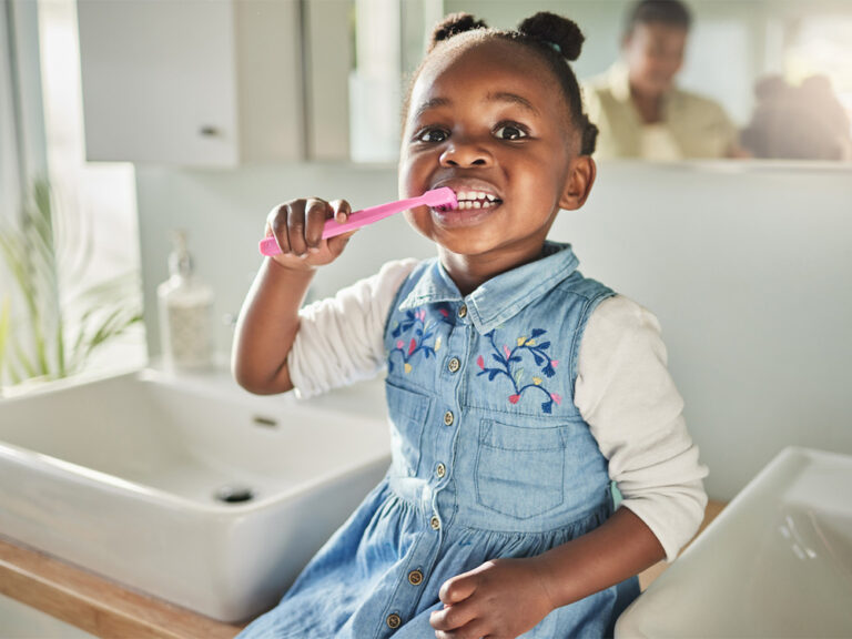 child brushing teeth while sitting on the counter