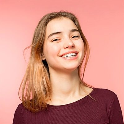 teen smiling in front of pink background