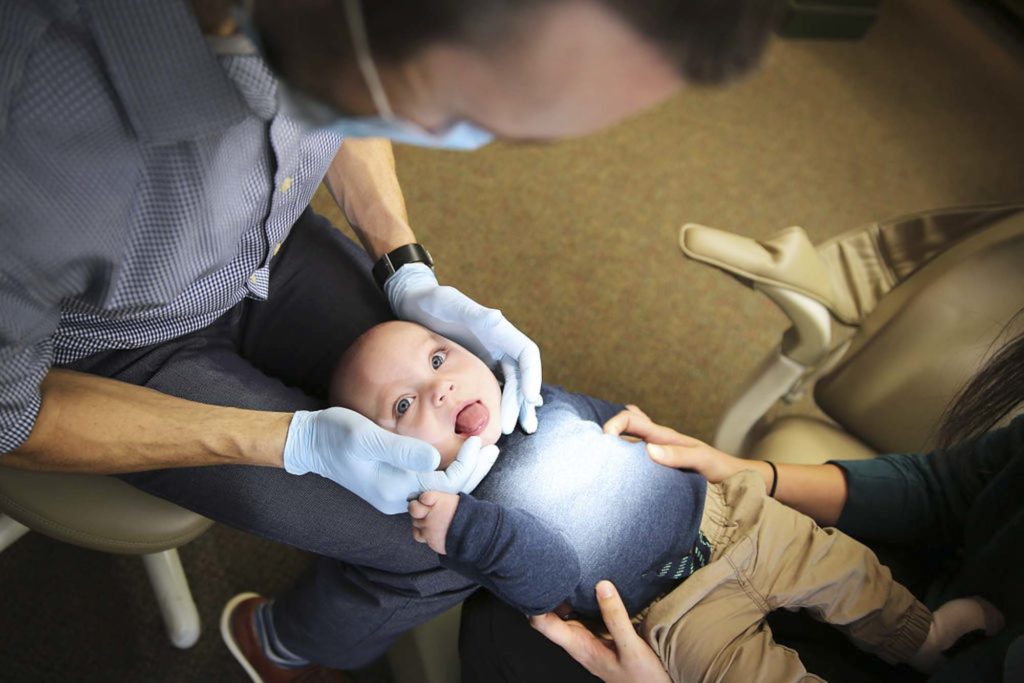 infant having their gums and mouth examined by a dentist