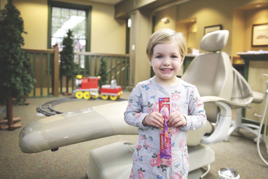 toddler holding a toothbrush at a dentist office